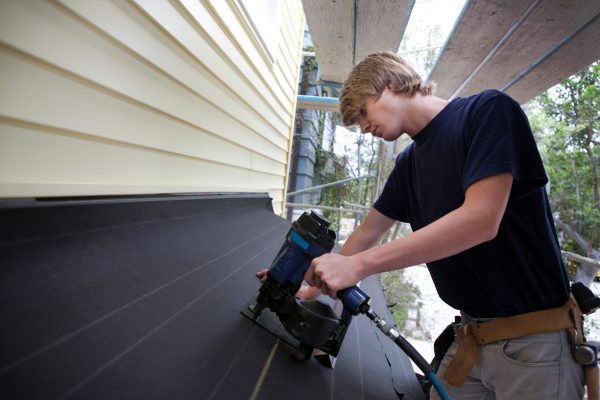 Teenage boy using nail gun on construction site
